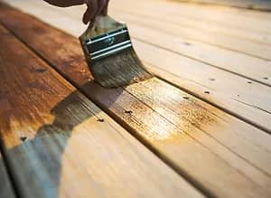 Holz wird mit schützendem Lack bepinselt